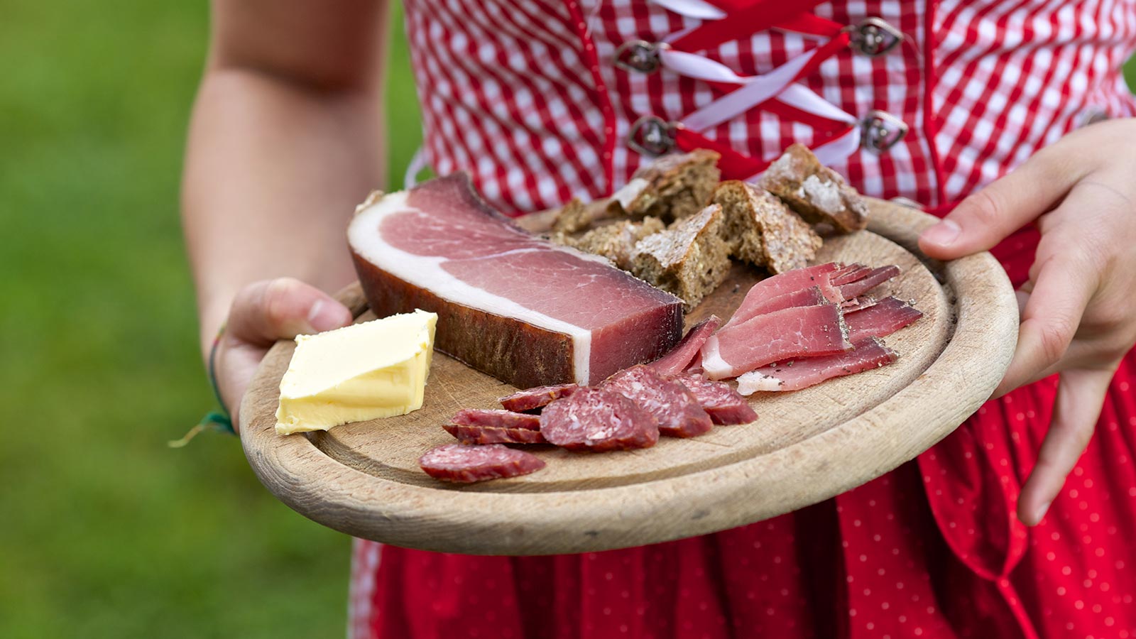 Ein Holzschneidebrett mit typischen Wurstwaren und Käse auf der Almhütte Midls Kosten in Ratschings