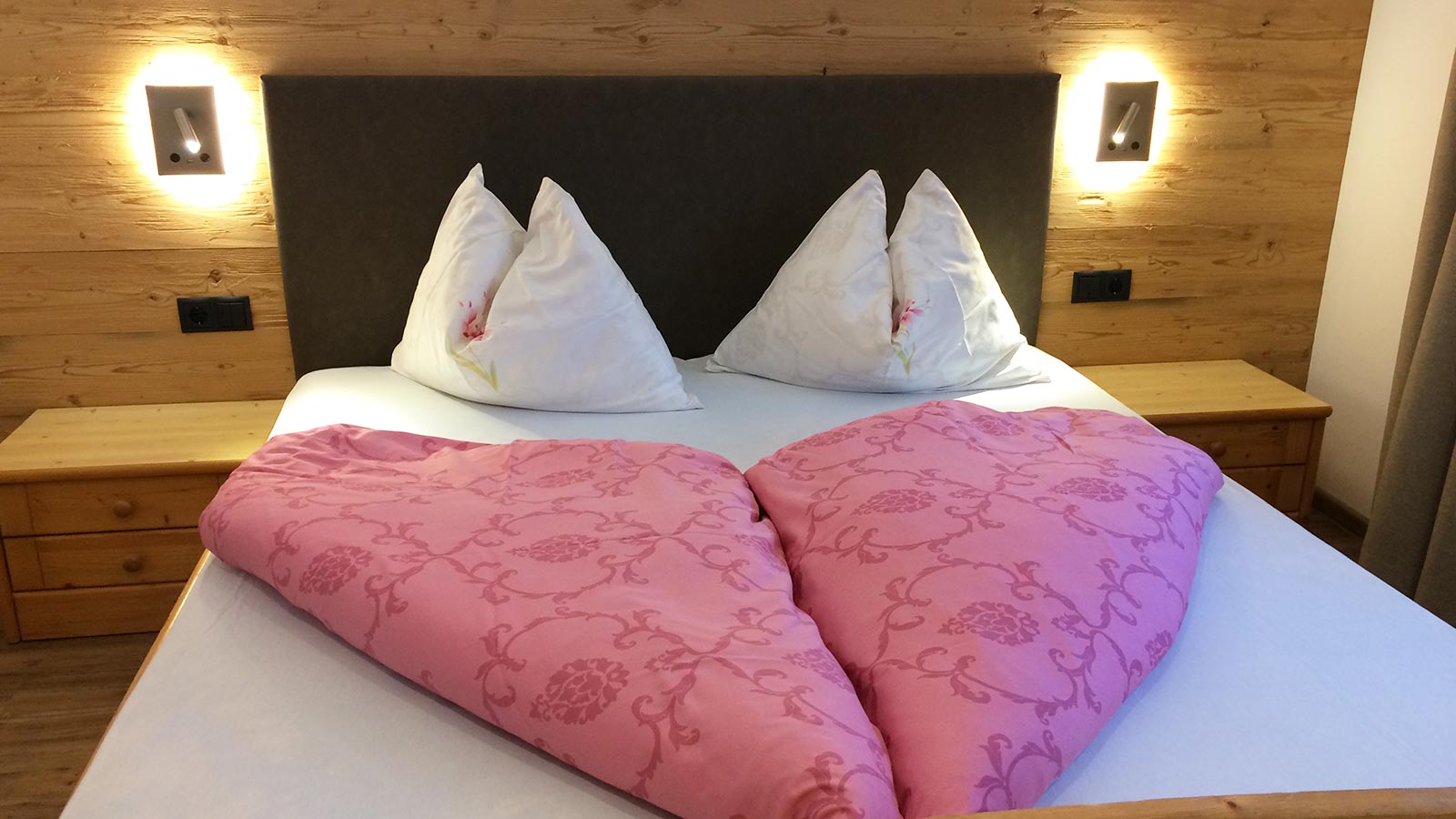 Dettaglio di un letto con lenzuola rosa di una delle camere da letto dell'Albergo Blosegg